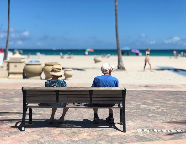 Retired couple sitting on a bench at the beach.